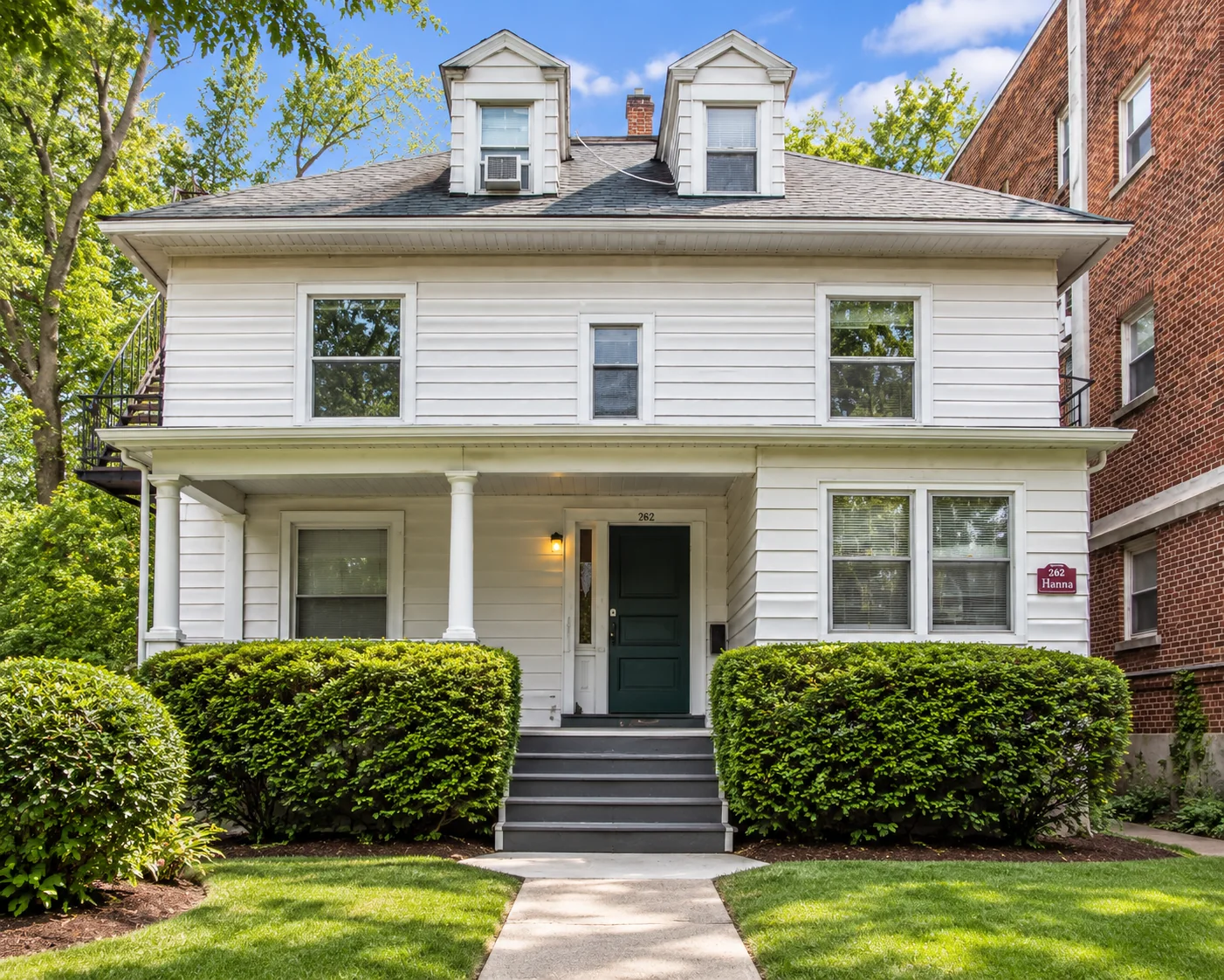 White multi-family house with a columned front porch at 262 S. Goodman St. in Rochester, NY