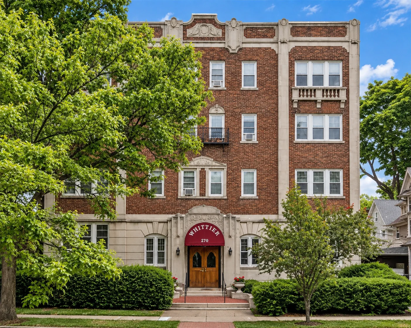 The Whittier, a historic brick apartment building with a red entry awning at 270 S. Goodman St. in Rochester, NY